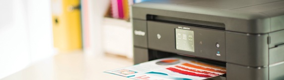 Svart Brother-skrivare på skrivbord som skriver ut ett färgglatt dokument